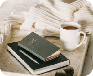 A food tray with a cup of coffee, diaries, and a pen.