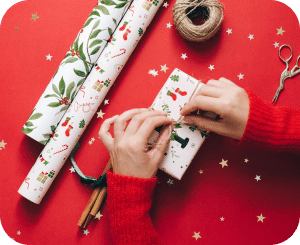 A holiday gift is wrapped against a cheerful red background.