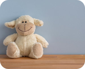 A charming stuffed sheep placed on a wooden table set against a blue background.