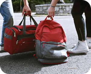 Hands carrying a backpack and a duffel bag.