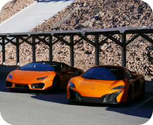 Bright orange sports cars under a parking shade.