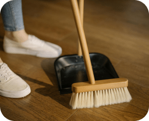 Broom and dustpan on a wooden floor.